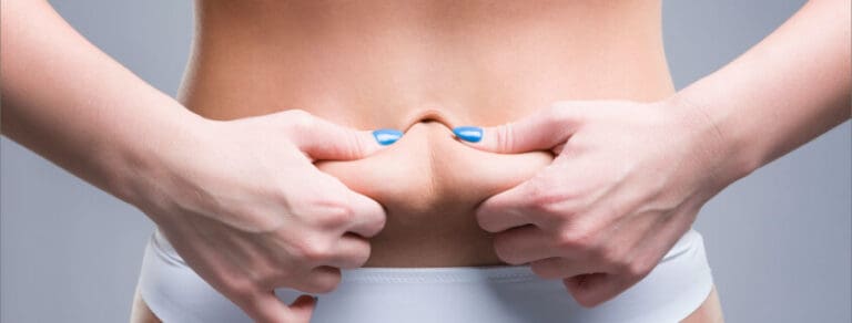 Nahaufnahme eines flachen Bauchs nach Bauchdeckenstraffung, Patientin zeigt stolz ihre Figur.