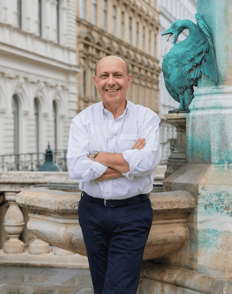 Dr. Edvin Turkof vor historischem Wiener Gebäude mit Brunnen